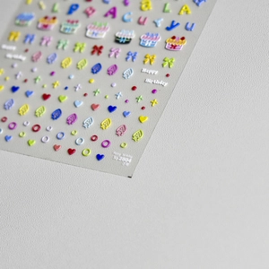 Macro detail of 3D embossed nail stickers featuring birthday cake and letter patterns