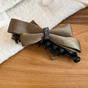 Close-up of elegant brown satin bow hair claw clip with crystal rhinestones detail