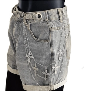 Close-up of silver multilayer belt chain with metal cross charms on denim shorts