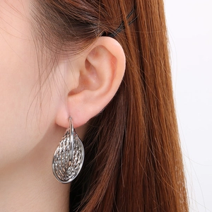 Gros plan d'un modèle portant des boucles d'oreilles argentées en U avec texture évidée