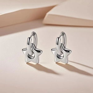 Close-up of silver titanium steel star earrings with minimalist polished hoop design