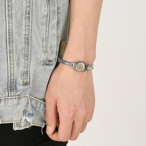 Detail of silver and gold zipper bracelet for men featuring a gear hub motif on wrist