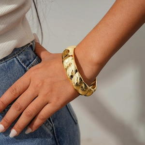 Detailed shot of golden chunky croissant bracelet with textured spiral metallic finish