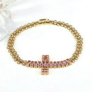 Close-up of gold chain bracelet featuring a cross pendant with pink zircon stones