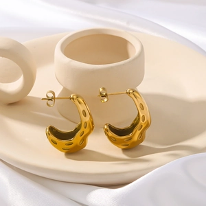 French vintage C-shaped gold stainless steel earrings with textured surface on silk background