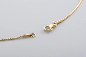 Macro view of gold snake chain necklace showing detailed lobster clasp and sturdy links