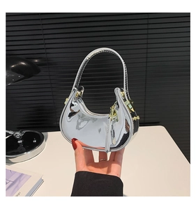 Close-up of a silver semi-moon handbag with a shiny metallic mirror finish and top handle