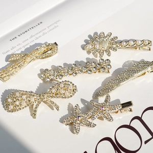 Set of 6 gold crystal hair clips with white pearls and rhinestones on white magazine