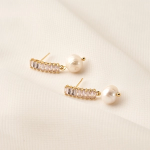 Detail of S925 silver earrings with gold finish, baguette zircons and baroque pearls