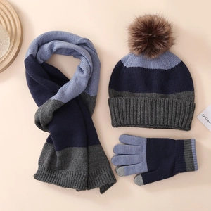 Flat lay of knit winter set including beanie with pompom, scarf and gloves in blue and grey
