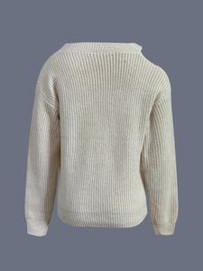 Dettaglio del maglione in maglia beige che mostra la trama spessa e le spalle cadenti