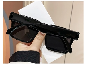 Detail view of large black square frame sunglasses with dark lenses and glossy finish