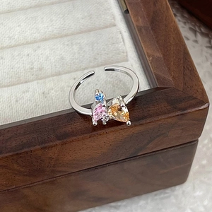 Close-up of adjustable silver ring with colorful cubic zirconia stones on a wooden box