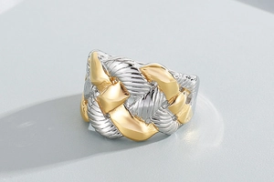 Macro detail of wide braided rope textured stainless steel ring in two-tone gold and silver