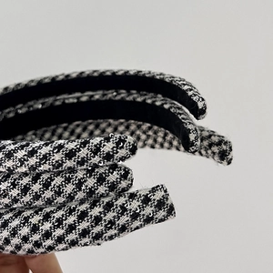 Close-up of houndstooth tweed headbands with sequins held by hand for texture detail