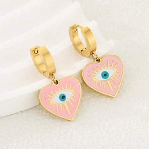 Détail de boucles d'oreilles créoles dorées avec cœur rose émaillé et œil protecteur