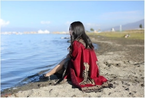 Ethnic red thick cashmere shawl wrap with gold patterns worn by a woman at the lakeside