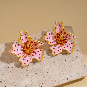 Macro detail of floral stud earrings with pink enamel petals on stone display