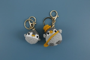 Detailed close-up of handmade crochet penguin keychain showing intricate yarn texture