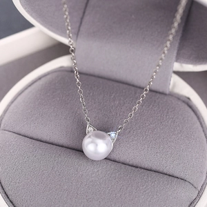 Close-up of cat ear pearl necklace with small crystals on a grey velvet jewelry box