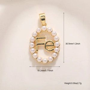 Macro d'un pendentif ovale doré avec perles et lettre Fe montrant les dimensions