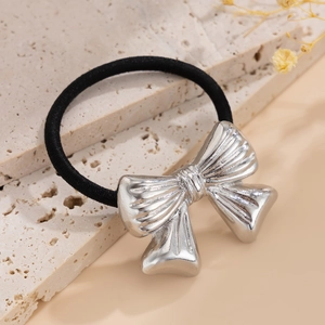Detailed view of silver metallic bow accessory on a black elastic hair tie for women