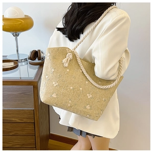 Détail du sac cabas en paille beige avec broderies florales et anses en corde