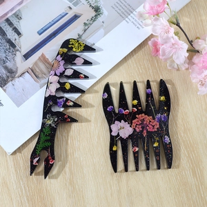 Detail view of handmade resin wide-tooth combs with embedded dried flowers and glitter