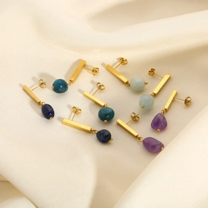 Detailed macro view of four geometric 18k gold earrings featuring natural stone pendants
