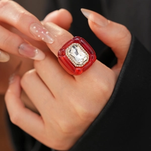 Vue macro d'une bague vintage en résine rouge avec cristal serti sur un doigt