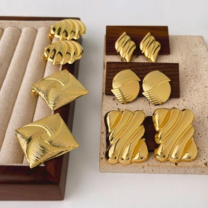 Chic geometric gold earrings with vintage textures displayed on a wooden jewelry stand