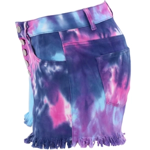 Macro detail of tie-dye denim shorts featuring raw fringe hem and silver button closure