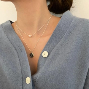 Close-up of layered 925 sterling silver necklace with pearl and vintage coin pendants