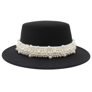 Détail d'un chapeau canotier noir avec ruban de perles blanches de style vintage chic