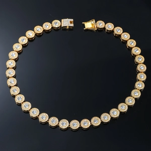 Detailed view of gold iced-out chain with round cubic zirconia and box clasp on black background