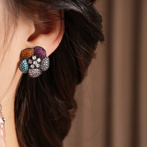Close-up of vintage flower earrings with colorful zircons worn by a female model