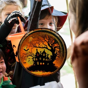 Detail of Halloween pumpkin house hanging ornament with metal chain in kids hand
