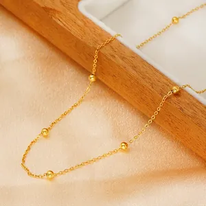 Minimalist gold stainless steel beaded necklace displayed on elegant satin fabric background