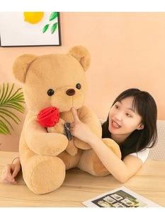 Mujer joven tocando la nariz de un gran oso de peluche marrón con una rosa roja en mano