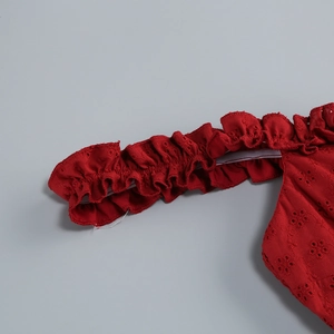 Close-up of red off-shoulder dress featuring intricate eyelet embroidery and ruffled details