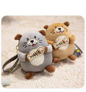 Close-up of cute plush sea otter charms in grey and khaki with colorful fish embroidery