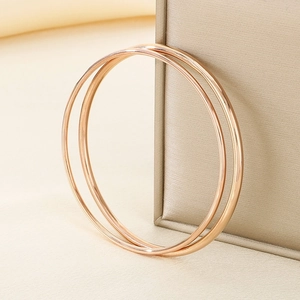 Detail of rose gold minimalist round bangles resting on a champagne jewelry box