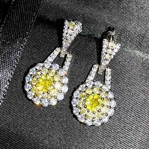 Macro shot of silver drop earrings with yellow center stone and white zircon halo