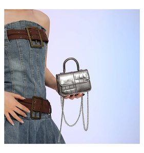 Silver embossed crocodile pattern mini bag with metal chain strap held by model