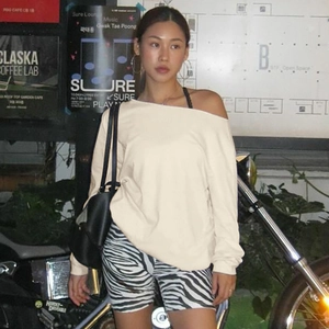 Detail of off-shoulder cream sweatshirt and zebra print shorts for a street style look