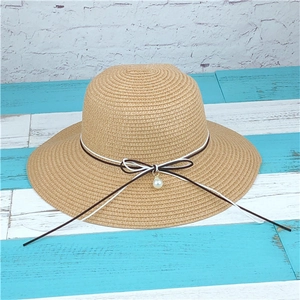 Detail of hand-woven straw sun hat showing pearl pendant and bicolor bow ribbon