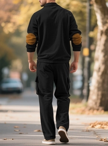 Detail of black corduroy tracksuit with brown elbow patches in an outdoor setting