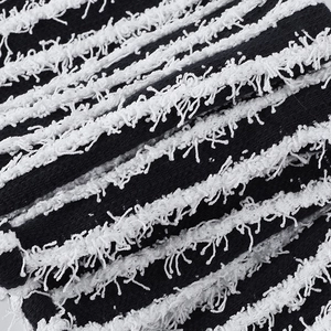 Détail macro du pantalon en maille rayé avec franges texturées douces noires et blanches