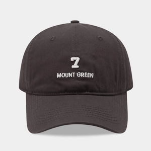 Detail van wit borduursel met nummer 7 en Mount Green tekst op een zwarte baseballpet