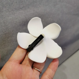 Close-up of white plumeria flower hair clip with black metal duckbill back attachment